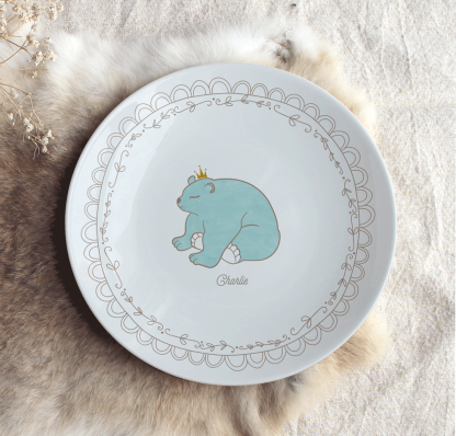 Assiette en porcelaine ours bleu entouré par un cercle effet dentelle avec prénom personnalisable.